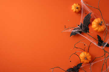 Halloween seasonal arrangement featuring pumpkins, decorative bats, cobwebs, and a bright orange...