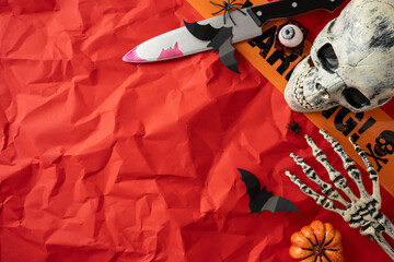 Halloween decorations displayed creatively on crinkled red paper, featuring pumpkins, a skull, and...