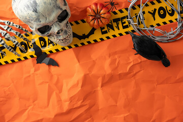 Spooky Halloween themed composition including a skull, skeleton, raven, and caution tape on orange