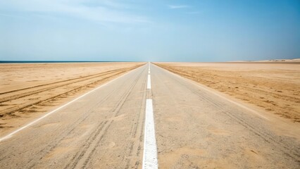 A long straight road stretches into the distance under a clear blue sky in a desert landscape