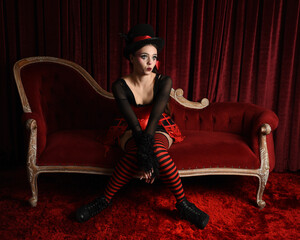 Burlesque circus performer, fantasy female model in gothic halloween jester clown costume with top...