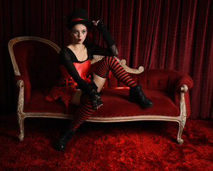 Burlesque circus performer, fantasy female model in gothic halloween jester clown costume with top...