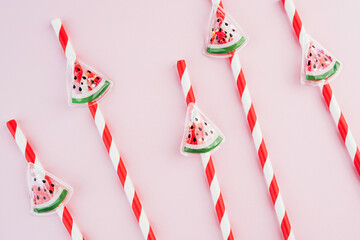  Closeup striped watermelon straws on pastel pink background for summer food concept