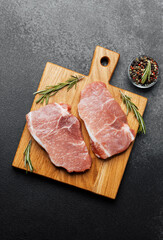 Fresh pork chops garnished with herbs on wooden cutting board