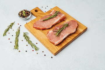 Fresh pork chops with herbs and spices on a wooden cutting board