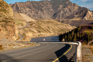 Highway road turns in mountains near big river at sunset time. Chujskij trakt, Siberia, Russia
