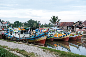 Traditional Indonesian wooden fishing boats rest quietly on calm river waters, their vivid colors reflecting a rich maritime heritage.