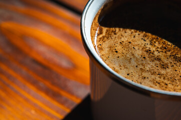  Close-up of fresh coffee with rich crema in a mug on a rustic wooden table. Warm, inviting natural...