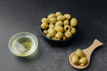 Green olives and olive oil on dark background