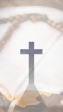 Animation of christian cross, rosary and holy bible over clouds