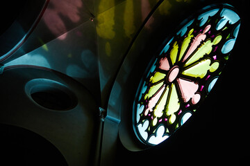 Stained glass window casting colorful light patterns inside church, intricate floral design...