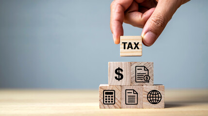 Close-up of hand placing wooden cube atop five-block pyramid on light wood surface, soft lighting