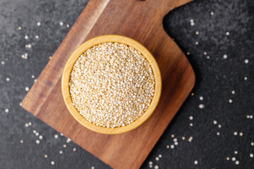 Quinoa seeds in wooden bowl on cutting board