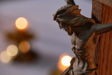 Wooden crucifix depicting Jesus Christ mounted on cross positioned in church interior with blurred...