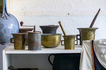 Collection of old brass mortars and vintage kitchenware displayed on a shelf. Traditional equipment...