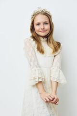 Joyful young girl in a cream lace dress with a crown, exuding innocence and charm in a minimalistic...