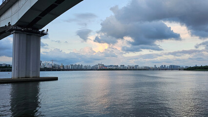 한강 다리 아래에서 바라본 서울 스카이라인과 석양 하늘