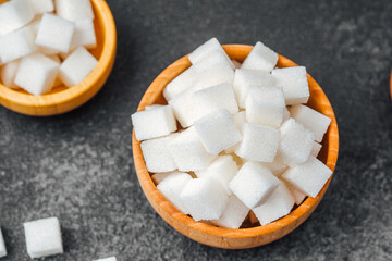 Sugar cubes arranged in wooden bowls on a dark countertop