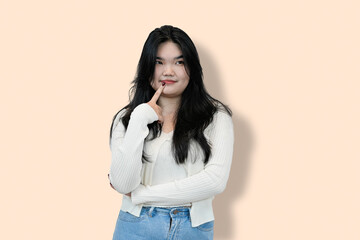 young chinese woman thinking and wondering in isolated beige background