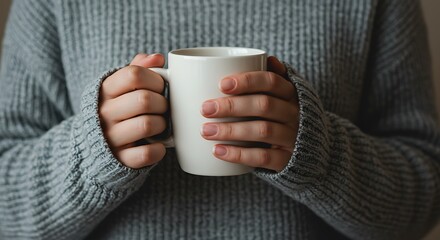Comforting scene with hands holding a beverage, wearing a textured grey jumper.


