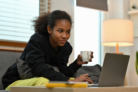 Focused Young African Woman Using Laptop with Coffee at Home