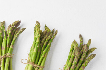 Fresh green asparagus bunches on white textured background