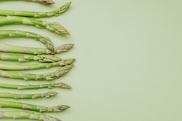 Side border of asparagus spears on green background with copy space