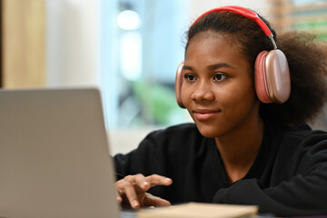 Young African Woman Using Laptop with Headphones, Focused Online Learning or Remote Work