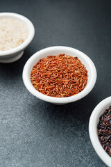 Three types of rice in bowls on dark background top view