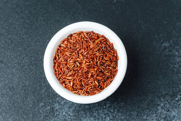 Close up of red rice in white bowl with scattered grains
