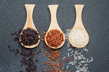 Three types of rice on wooden spoons black red and white grains