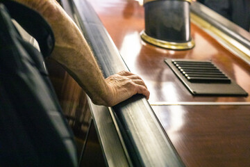 elderly man's hand holding the railing on the escalator