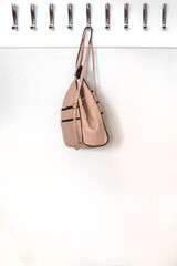 light leather backpack hanging on a hanger with metal hooks in a classroom, office. Back to school