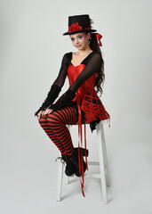 Burlesque circus performer, fantasy female model in halloween jester clown costume with top hat,...