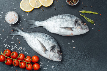 Top view of raw dorado fish with lemon pepper and rosemary on black background