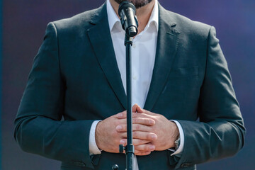 A confident speaker addressing the media during a press conference, standing at a podium with...
