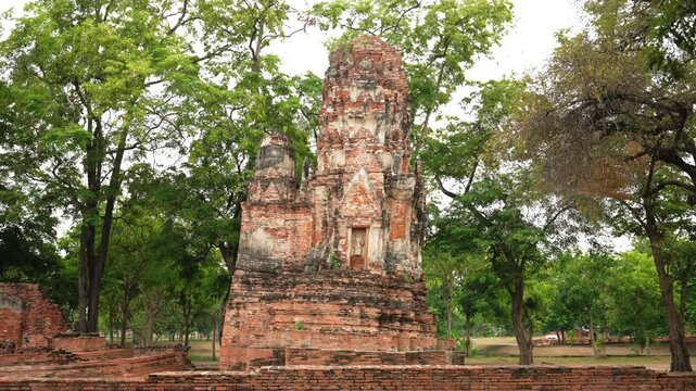 Ancient Leaning prang tower ruins amid trees in Wat Nok, Ayutthaya Historical Park, Thailand