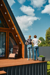 Back view of mother and daughter standing on terrace of tiny house