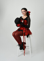 Burlesque circus performer, fantasy female model in halloween jester clown costume with top hat,...