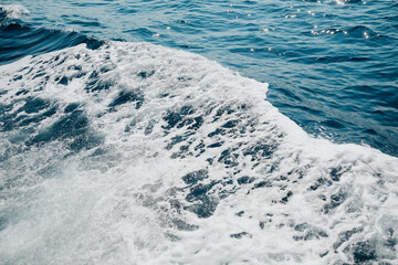Close up of foamy ocean waves with glistening sunlight reflections