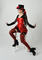 Burlesque circus performer, fantasy female model in halloween jester clown costume with top hat,...
