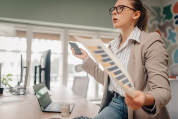 Interior designer comparing color swatches with phone in office