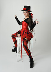 Burlesque circus performer, fantasy female model in halloween jester clown costume with top hat,...