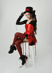 Burlesque circus performer, fantasy female model in halloween jester clown costume with top hat,...