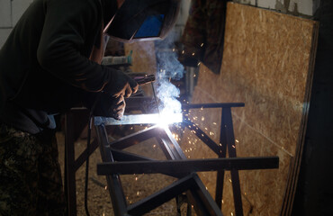 A man is welding metal in a workshop