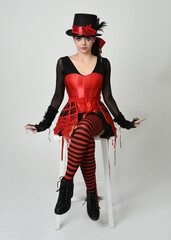 Burlesque circus performer, fantasy female model in halloween jester clown costume with top hat,...