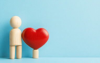 Wooden mannequin holding red heart symbolizing love and romance on wooden background