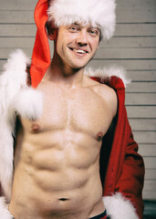 Young attractive man with athletic body posing in Santa Claus costume.