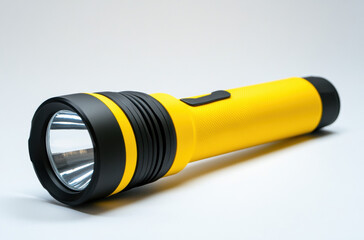 Yellow flashlight on white background with LED and battery-powered light