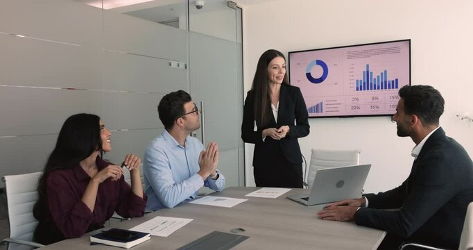 Positive confident product manager woman presenting marketing research results on corporate stakeholders meeting, giving project tasks to employees, talking to colleagues at large table